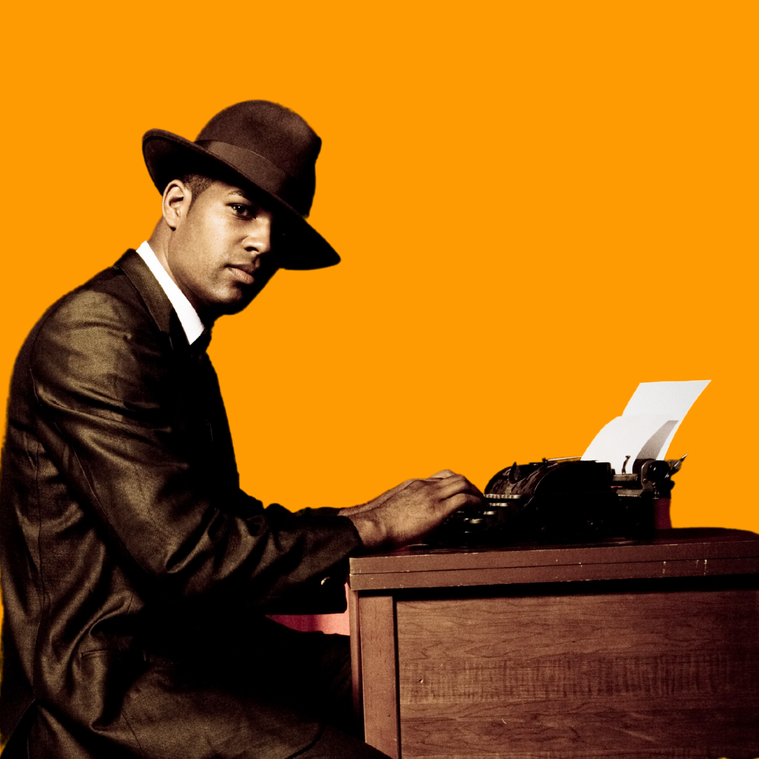 Man in vintage 1940's clothing in front of a vintage typewriter